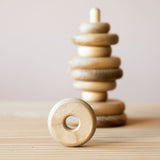 Der große Steckturm für Babys von Kokomoo: acht Holzringe sind, nicht nach Größe geordnet, auf die Steckbasis geschoben, einer steht davor auf seiner runden Kante.