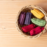 Sechs Paar Stulpen von Kokomoo in den Farben Mais, Limette, Kirsche, Fuchsia, Rosenholz und Lavendel liegen in einem Korb.