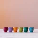 Die 6 Grapat "Mates" Holztöpfchen in Erdfarben nebeneinander in einer Reihe.