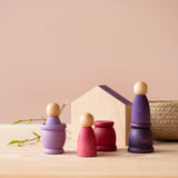 3 Grapat Nins in Lila-Tönen, passende 3 Grapat Mates Töpfchen dazu, dahinter ein kleines Haus au Holz und ein Körbchen.