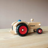Der Fagus Traktor aus Holz von der Seite, eine Spielfigur sitzt im Traktor.