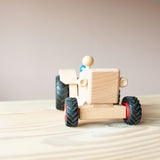 Der Fagus Traktor aus Holz von vorne, eine Spielfigur sitzt im Traktor.