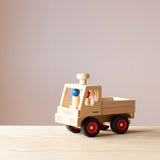 Der Fagus Unimog aus Holz von schräg vorne fotografiert, im Führerhaus sitzen die beiden Fagus Holzfiguren mit rotem und blauem Kopf.