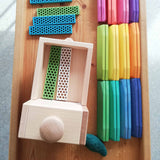 Der Fagus Unimog aus Holz von oben fotografiert, auf der Ladefläche sind 2 Bioblo Bausteine, daneben liegen verschiedene bunte Bausteine und warten verladen zu werden.