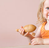 Ein Kleinkind hält die Babyrassel Urfisch von Kokomoo in der Hand.