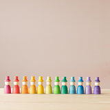 Die 12 "Wizards" Zauberer Spielfiguren aus Holz von Grapat stehen sortiert nach den Regenbogenfarben in einer Reihe.