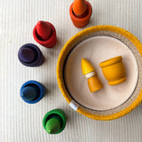 Das Kokomoo Bunte Zwerge Spielset für Babys ab 1 Jahr mit in einem Jutekorb mit gelbem Rand, einer Holzschale und den Grapat Mates und Grapat Tomtens in Regenbogenfarben. Alle Spielmaterialien sind gut zu sehen von oben.