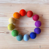 Ein Kreis gelegt, farblich sortiert, mit den Filzbällen in zwölf Regenbogenfarben.