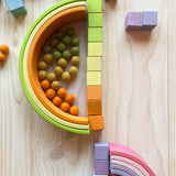 Die Boegen des großen Regenbogen Pastell von Grimms in gelb- und orange- und LindGruentoenen, zusammengelegt mit den farblich passenden Wuerfeln vom Grimms Mosaik Pastell