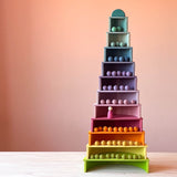 Die Boegen des großen Pastell Regenbogen von Grimms und halbkreisrunde Bauplatten von Grimms sind zu einem Turm aufgebaut. In jeder Etage liegen kleine Filzkugeln in den passenden Farben.
