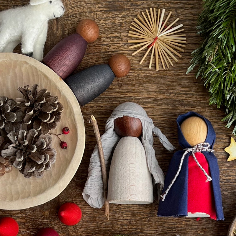 Zwei kleine Holzfiguren von Grapat, mit Stoffen zu Maria und Josef verkleidet, darüber ein Weihnachtsstern aus Stroh.