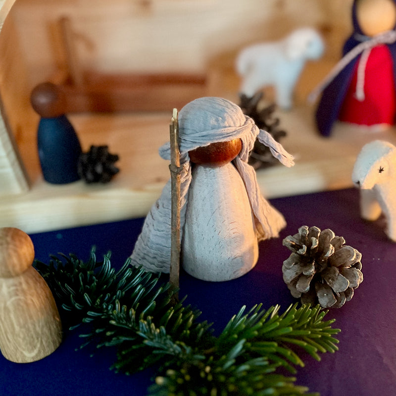 Ein  Grapat "Adult Nin" mit dunkler Hautfarbe verkleidet als Josef aus der Weihnachtskrippe, vor ihm ein Tannenzweig.