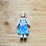 Ein handgefertigtes, blondes Waldorf Biegepüppchen mit weißem Oberteil und blauem Rock.