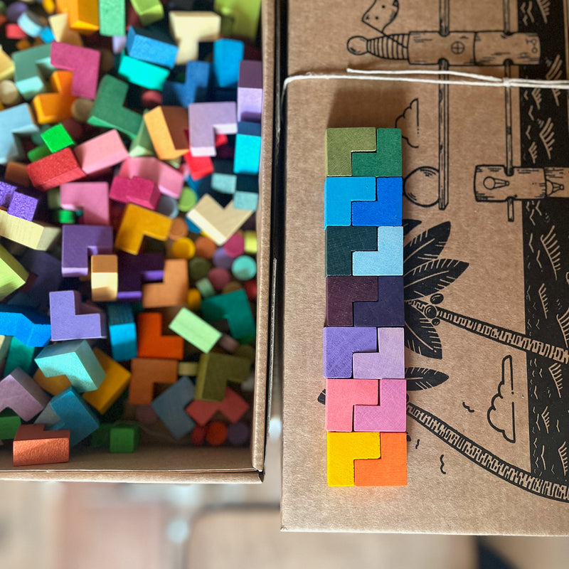 Drausicht auf kleine bunte L-förmige Bausteine, die in einer bunten Reihe aneinandergelegt sind.