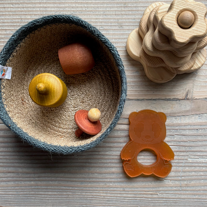 Ein Geschenkseit für Babys ab 1 Jahr: In einem Jutekörbchen liegen Grapat "Little Things" in gelb und braun, daneben eine Baby Beißring Kleiner Panda aus Naturkautschuk und ein kleiner Steckturm aus Holz.