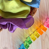 Lichtbausteine Quader Pastell von Bauspiel aufgereiht mit ihrem Licht-Schattenspiel, daneben ein Korb mit Seidentüchern.