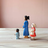 Ostheimer Spielfiguren aus Holz, nämlich ein Baby im Strampler, eine Frau und ein Mädchen mit rotem Kleid, weißer Schürze und Kopftuch mit Punkten darauf.