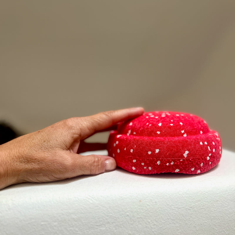 Eine Hand hält den rot-weiß gesprenkelten Mini-Stapelstein Confetti Red&Blush.