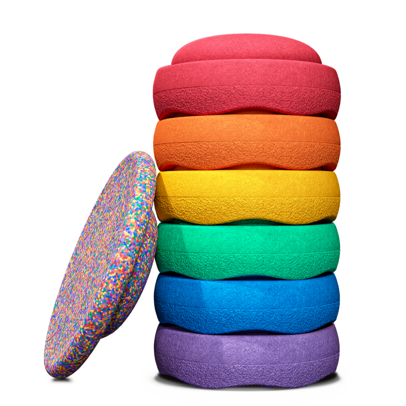 Ein gestapeltes Stapelstein Bundle Classic in Regenbogenfarben, daran lehnt ein Confetti Board.