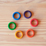 Die Grapat Rings Holzringe in den sechs bunten Regenbogenfarben liegen im Kreis.