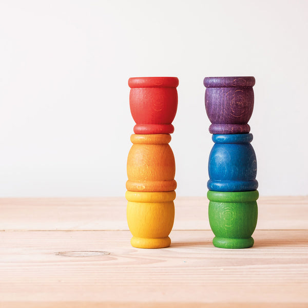 Grapat "Mates" Toepfchen aus Holz in 6 Regenbogen Farben stehen als zwei Saeulen zu je 3 gestapelten Toepfchen nebeneinander.
