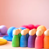 Ein Blick von vorne auf nebeneinander aufgereihte Nins Holzfiguren in den Farben - von links nach rechts - grün. blau, lila. rot, orange.