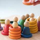 Grapat "Nins, Rings & Coins" buntes Holzfiguren-Set, es sind gestapelte Ringe und darin versteckte Nins Spielfiguren in den bunten Regenbogenfarben zu sehen,
