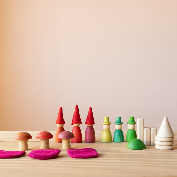 Ein Blick von vorne auf alle Teile des Spielesets Freunde im Wald von Grapat. 3 rote und 3 gruene Kegel, 3 Holzpilze und Naturholzquarder, Kegel und Scheiben