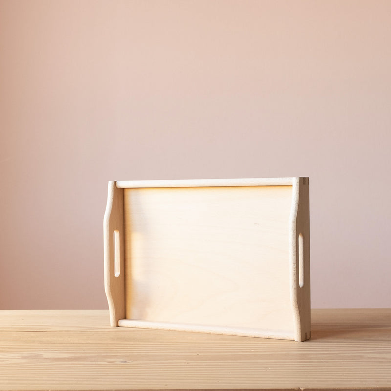 Das kleine Tablett aus Birkenholz von Kokomoo, aufgestellt auf der langen Kante. Holzmaserung und Griffe sind gut zu sehen.